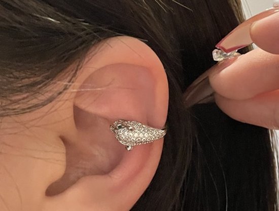 Zilverkleurige panter ear cuff bezet met steentjes, gedragen op een oor.