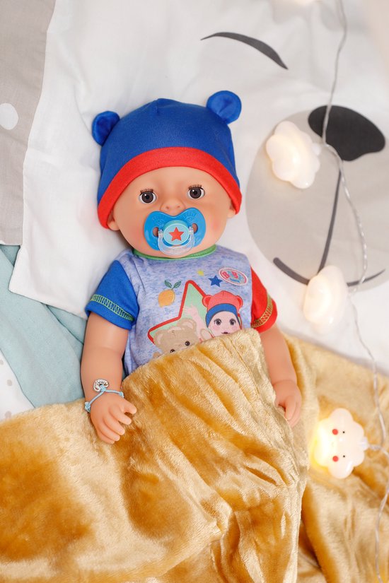 BABY born pop in bed met blauwe muts, romper en tutje. Met gouden deken.