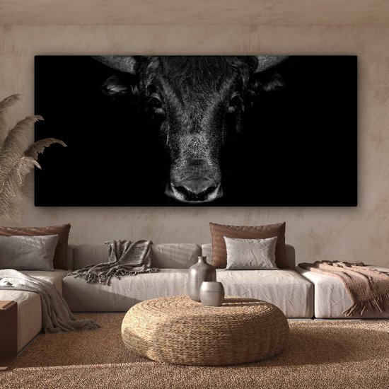 Toile noir et blanc avec une tête de taureau comme point central, au-dessus d'un canapé tendance.