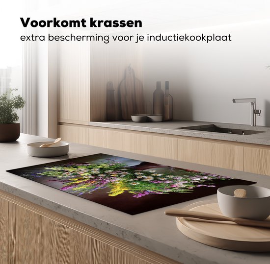 Een inductiebeschermer met een boeket bloemen, geplaatst op een aanrecht in een moderne keuken.
