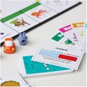 Een oranje autootje en een blauwe hond speelstuk naast een 'Chance'-kaart op een Monopoly Junior bord.
