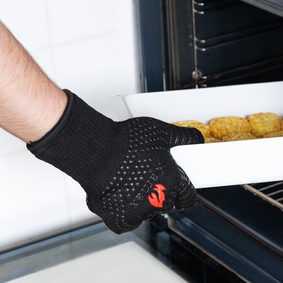 Handen met zwarte, hittebestendige handschoenen met siliconen noppen, nemen een ovenschotel uit de oven.