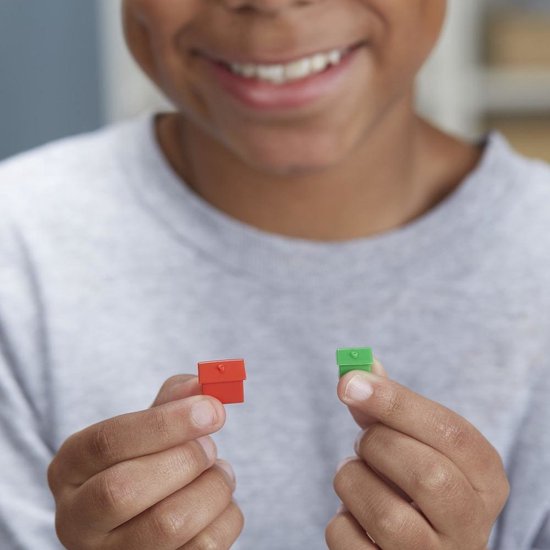 Kind met Monopoly huizen: een rood en een groen huisje.