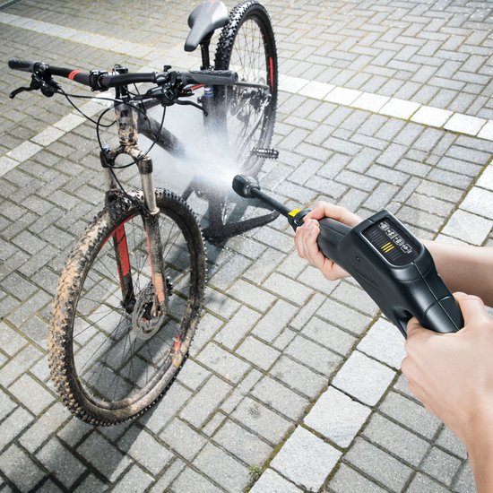 Fiets met modder wordt schoongespoten met hogedrukreiniger, rode details op frame.