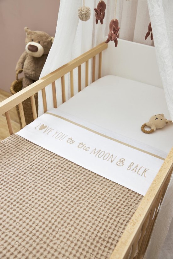 Wieg met een beige wafeldekentje, een wit hoeslaken met de tekst 'LOVE YOU to the MOON & BACK' en een knuffel.