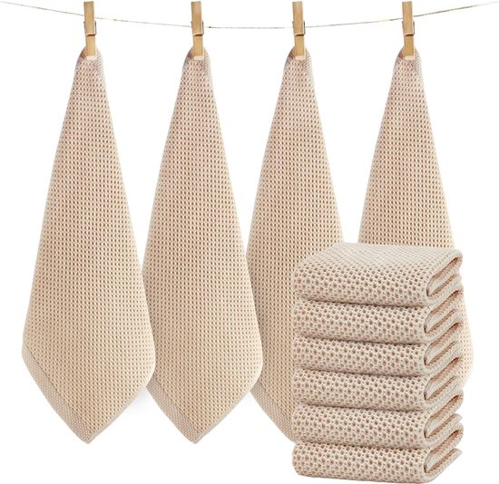Vier beige keukendoeken met wafelpatroon hangend aan een waslijn en een stapel van zes.