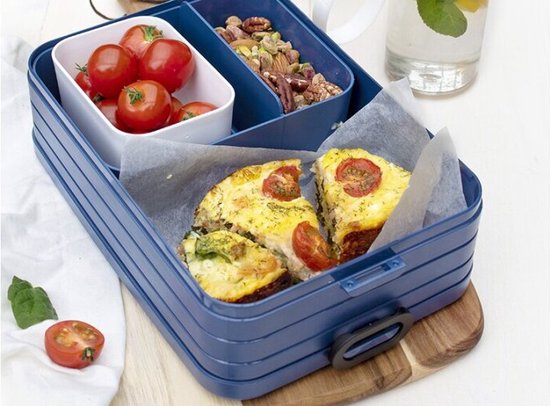 Boîte à lunch bento bleue avec quiches, tomates cerises et un compartiment avec mélange de noix.
