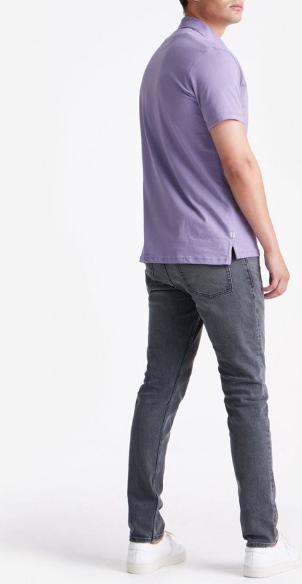 Achterkant van een man in een lavendelkleurig poloshirt met korte mouwen en grijze jeans, staand.