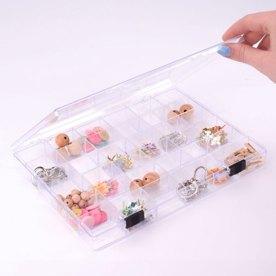 Boîte de rangement transparente à 36 compartiments, couvercle ouvert par une main avec vernis à ongles bleu.