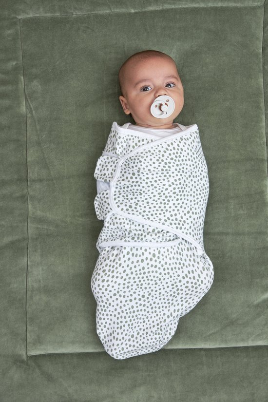 Baby ingebakerd in een doek met groene stipjesprint en een speentje.