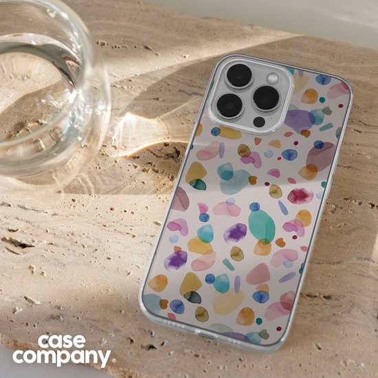 Telefoonhoesje met multicolour waterverf terrazzo patroon op een lichte achtergrond, naast een glas water.