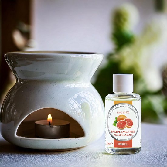 Flesje Pamplemousse parfum naast een witte olielamp met brandende kaars.