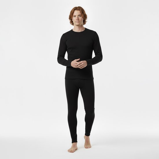 Man in zwart thermoshirt met lange mouwen en een thermolegging, staand met handen gevouwen.