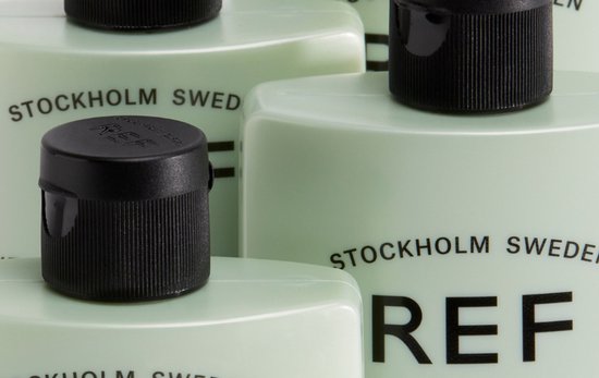 Gedetailleerde close-up van lichtgroene REF Stockholm flessen met zwarte doppen.