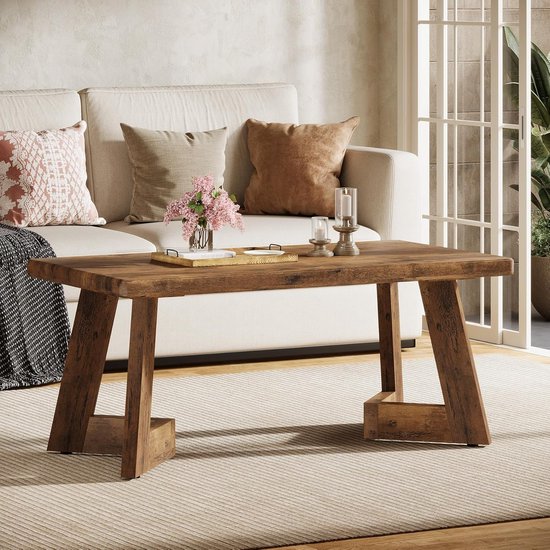 Bruine houten salontafel met verweerd oppervlak in een woonkamer met een bank en open haard.
