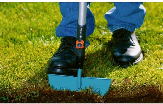 GARDENA graskantsteker met blauw metalen blad, in gebruik met zwarte schoenen en blauwe spijkerbroek.