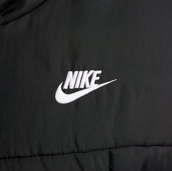 Detail van het witte Nike logo geborduurd op een zwarte pufferjas.