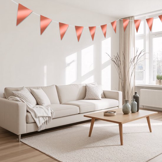 Un salon avec un canapé beige et une table basse, décoré d'une guirlande couleur cuivre.