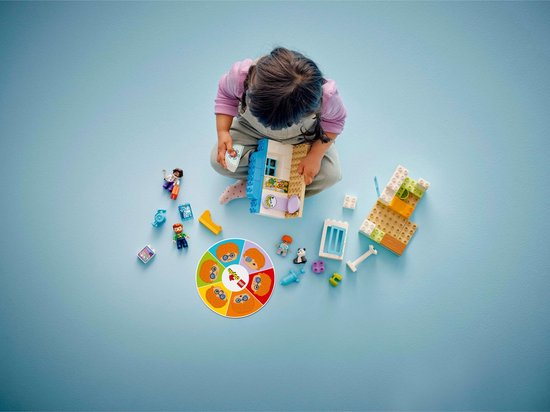 Meisje speelt met LEGO Duplo dokterscentrum. Losse onderdelen, figuren en draaischijf met emoties.
