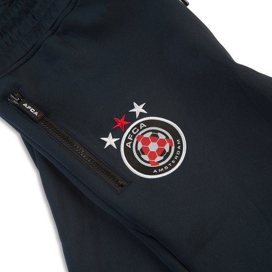 Detail van een donkerblauwe trainingsbroek met AFCA logo en ritszak.