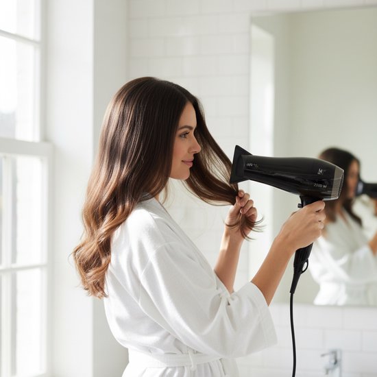 Vrouw met lang bruin haar in witte badjas, droogt haar haar met een zwarte Lafe haardroger.