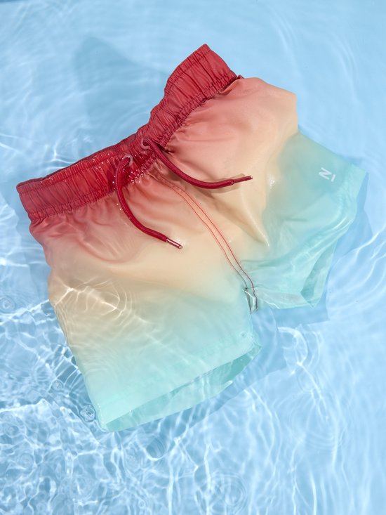 Natte rode, oranje en lichtgroene zwembroek in het water.