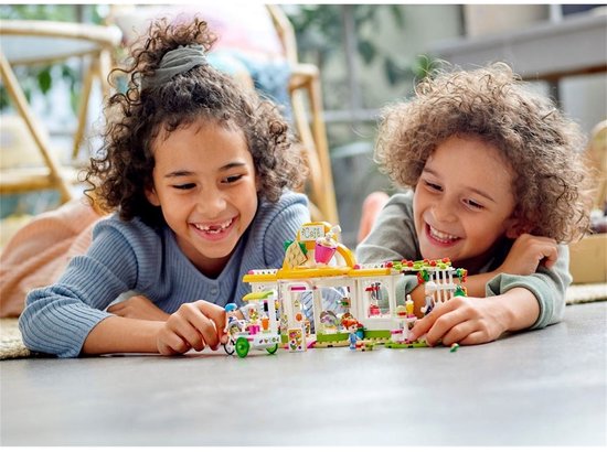 Twee lachende kinderen spelen met een LEGO Friends-café.