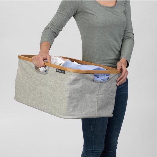 Vrouw met grijze Brabantia wasmand gevuld met wasgoed.