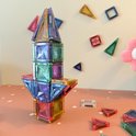 Paarse, groene en gele magneetstenen vormen een toren op een roze tafel met witte stippen.