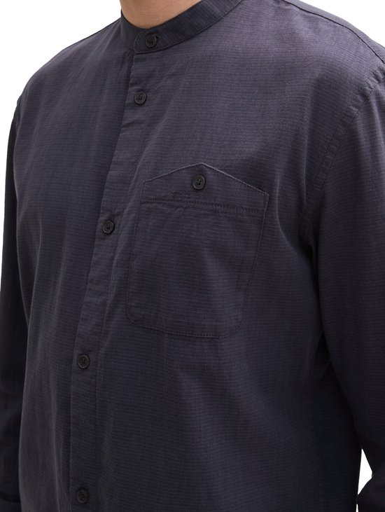 Donkerblauw overhemd met opstaande kraag, knoopsluiting en borstzakje.