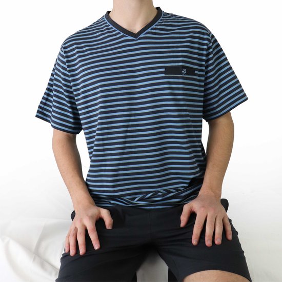 Man zittend in een gestreept blauw/zwart T-shirt met V-hals en zwarte short.