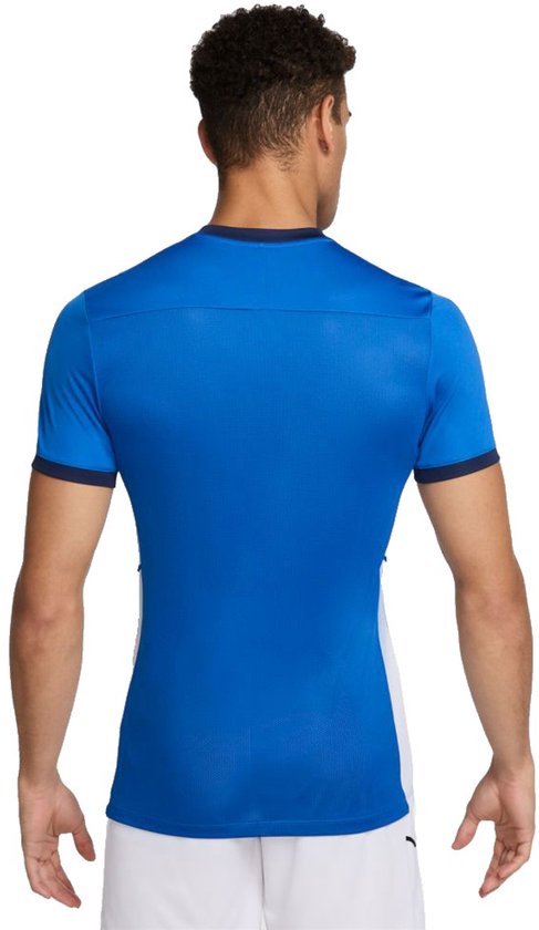 Blauw sportshirt met donkerblauwe boorden, gedragen door een man.