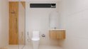Zwarte infrarood heater boven een toilet in een moderne badkamer met douchecabine.