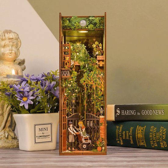 Houten boekensteun met een tuinpoort, klimop en drie figuren.