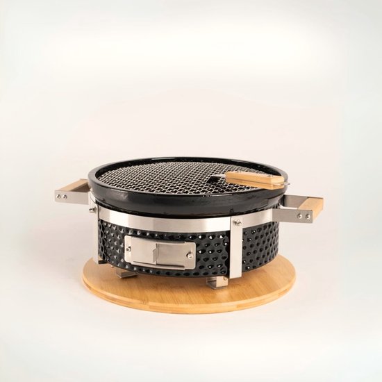 Zwarte, ronde hibachi BBQ op een houten onderstel met bamboe handvatten, op een witte achtergrond.