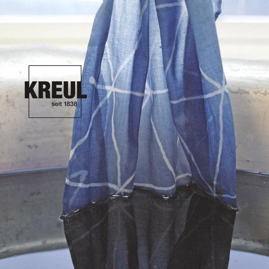 Tissu bleu avec un motif de lignes blanches tenu dans une cuve de liquide sombre.