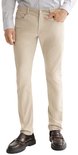 Model draagt een beige broek, gecombineerd met een licht overhemd en donkere schoenen.