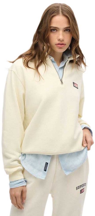 Model met een off-white, halve rits trui met kraag en een kleine Amerikaanse vlag badge op de linkerborst.