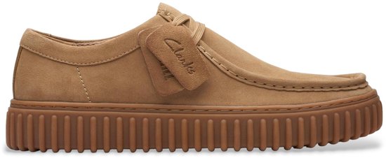 Bruine suède schoen met kreukelige crêpezool, strikdetail en Clarks-label.