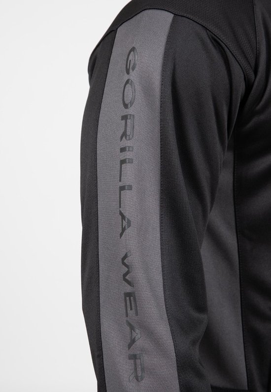 Detail van een zwarte mouw met grijze bies waarop GORILLA WEAR staat.