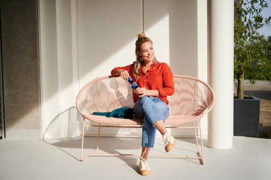 Vrouw in oranje blouse met een Mepal waterfles met blauwe dop en band.