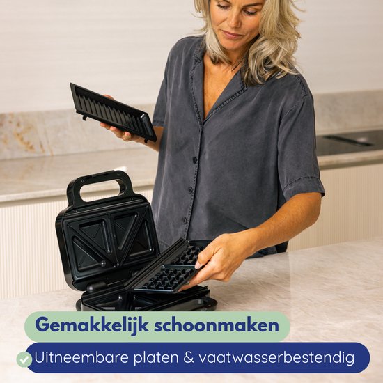 Vrouw houdt uitneembare wafelplaten vast van een zwart wafelijzer. Makkelijk schoonmaken.