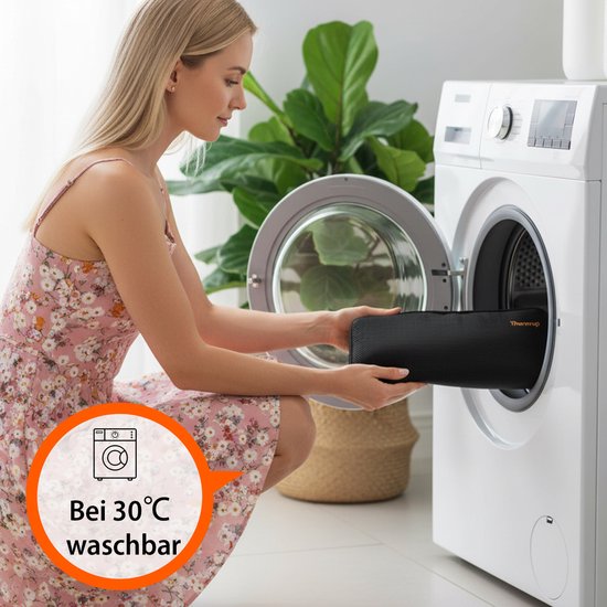 Vrouw met blond haar in een jurk legt een zwart verwarmd zitkussen in een wasmachine. Tekst: 'Wasbaar op 30°C'.