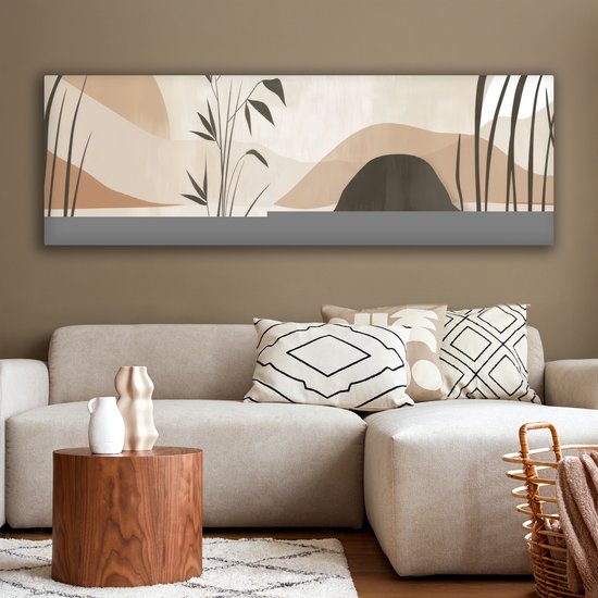 Abstract schilderij in beige tinten met donkere planten en heuvelvormen boven een hoekbank.