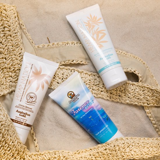 Drie crèmes van Australian Gold op een rijtje op het zand: Hemp Nation met palmbomen, Hemp Nation Sandalwood en Forever After All Day Moisturizer.