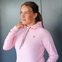 Jongedame in een lichtroze vest met capuchon en rits, handen in de zakken.