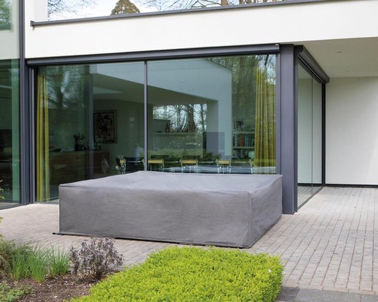Grijze beschermhoes over een L-vormige loungeset, geplaatst op een terras bij een moderne woning.