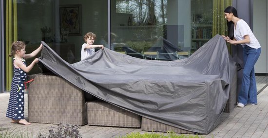 Vrouw en kinderen leggen een grijze beschermhoes over een bruine, gevlochten loungeset.