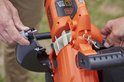 Handen maken een deel los van oranje BLACK+DECKER bladblazer met metalen haak.
