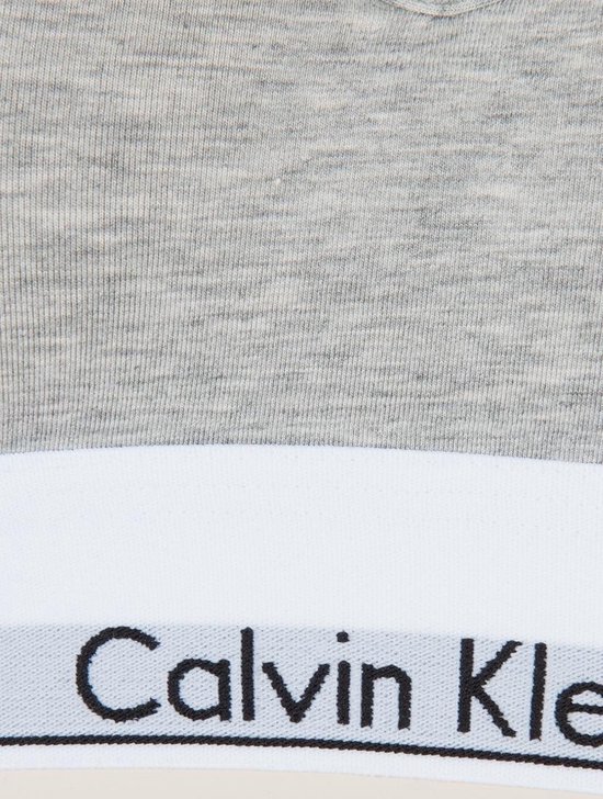 Detail van een grijze Calvin Klein bralette met witte band met logo.